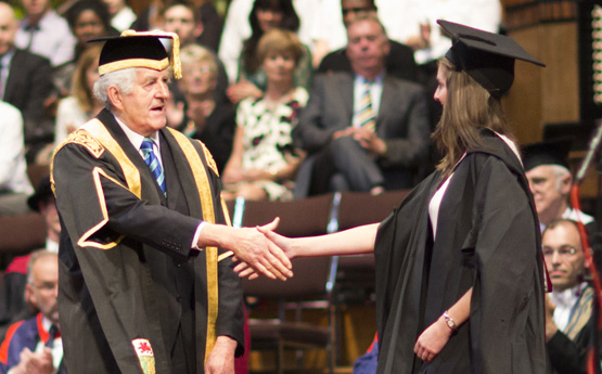 The vice-chancellor shaking a student's hand at a graduation ceremony.