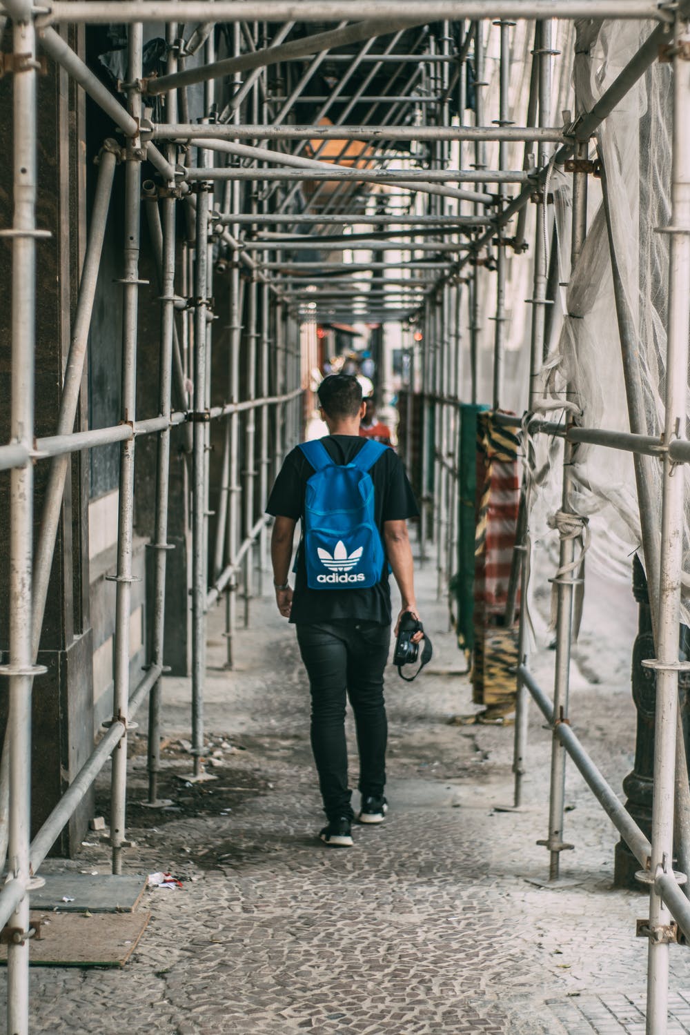 a man walking beneath some scaffolding