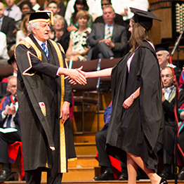 chancellor shaking a student's hand on stage at graduation