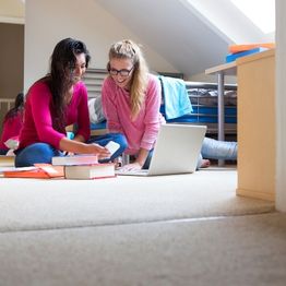 Two students sitting on floor of student accommodation room