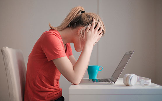 Girl with head in hands at her computer.