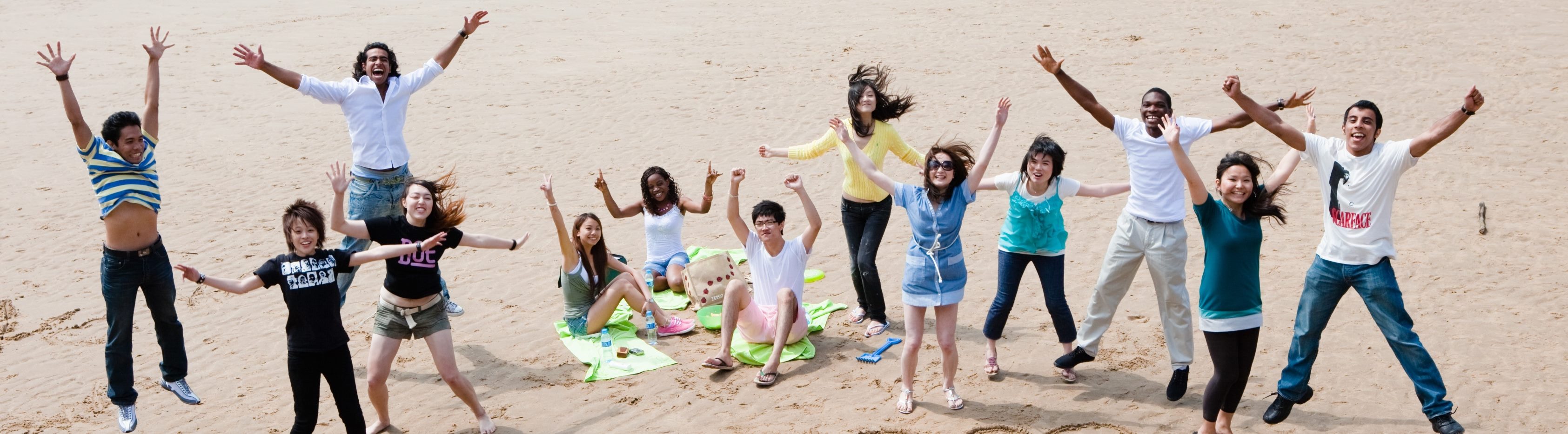 Photograph of students jumping in the air on Swansea Bay beach.