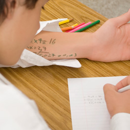 Person cheating in an exam with notes written on arm
