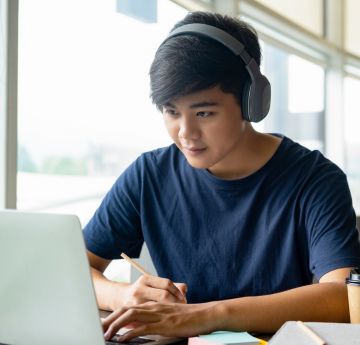 Student wearing headphones using a laptop