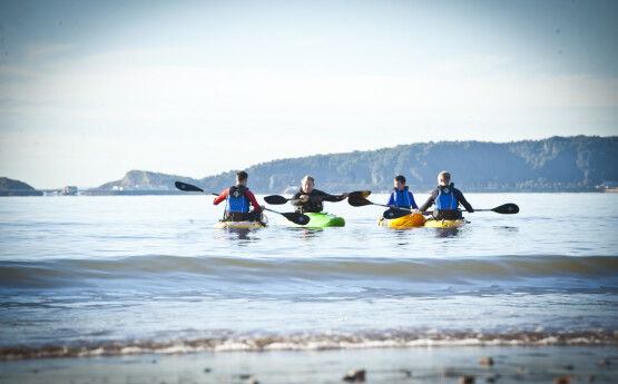 Four students kayaking in Swansea Bay