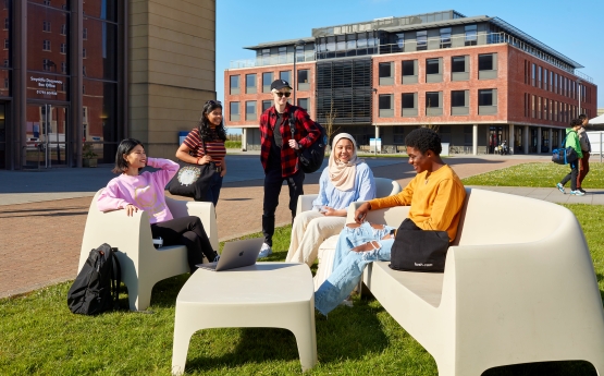 Five students using the outside seating in front of the Engineering Building on Bay Campus.