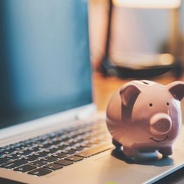 Piggy bank next to laptop 
