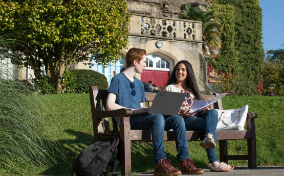 Students sitting on a bench chatting on Bay Campus