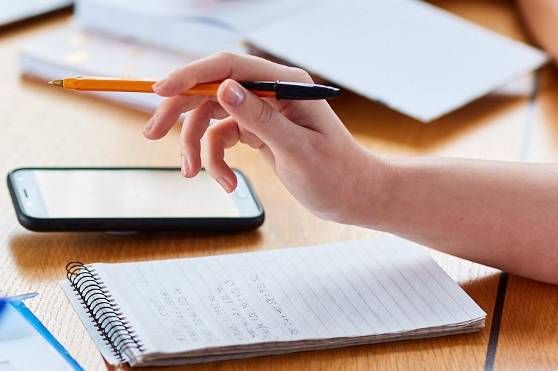 Hand holding a pen above a notebook