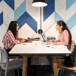 Picture of two female students talking across a table