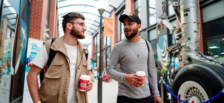 Student walking in Engineering Central with coffee