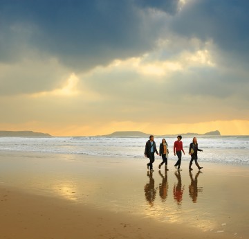 Four students walking along a beach 