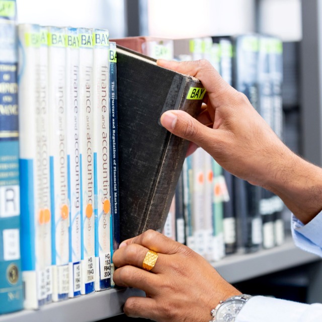 A hand removing a book from a library shelf