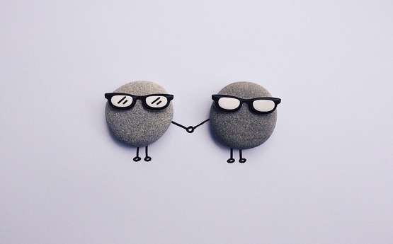 Two cartoon pebbles wearing glasses and holding hands
