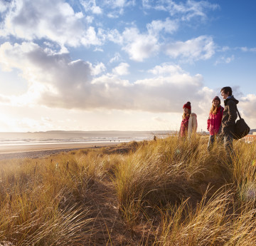 Three students standing on the dunes at bay campus looking out to sea