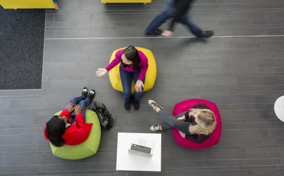 Aerial shot of three students sitting on bean bags chatting in communal area