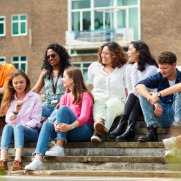 Students sitting on the steps of Fulton House, Swansea University